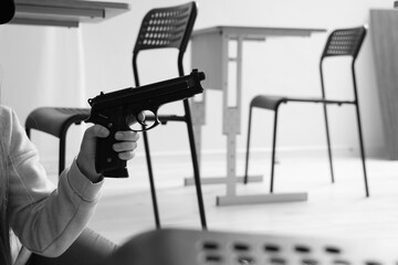 Female student with gun in classroom, closeup