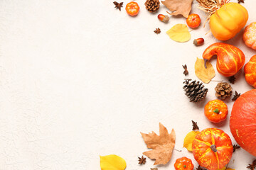 Autumn composition with ripe pumpkins, pine cones, spices and fallen leaves on light background
