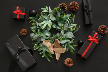 Christmas mistletoe wreath with balls, cones and gift boxes on black background