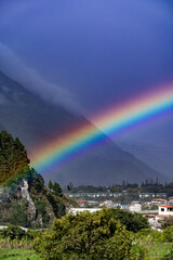 Beautiful view of the rainbow over the  volcanoes in the city of Banos, Ecuador. Amazing sunset.
