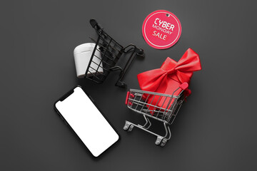 Composition with shopping carts, gadgets and gift box on black background. Cyber Monday sale