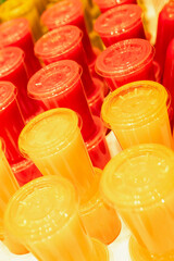 Colorful plastic glasses with juice in a row, closeup of photo