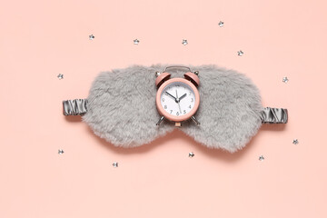 Composition with stylish sleep mask and alarm clock on pink background