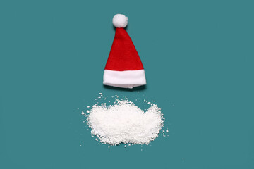 Santa hat and beard made of snow on color background