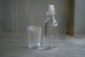 Glass of water with a bottle on gray background floor. Healthy lifestyle. Bottle with clean and fresh drinking water