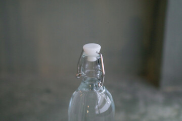Bottle of water on gray background floor. Healthy lifestyle. Closeup of glass bottle and glass full of fresh water.