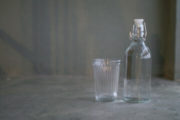 Glass of water with a bottle on gray background floor. Healthy lifestyle. Bottle with clean and fresh drinking water