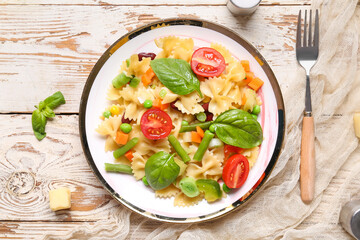 Plate with tasty pasta primavera on white wooden background