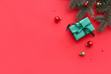 Gift box with Christmas tree branches and balls on red background