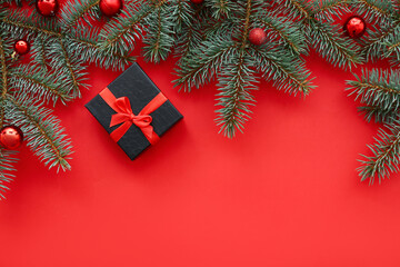 Black gift box with Christmas tree branches and balls on red background