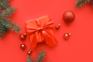 Gift box with Christmas tree branches and balls on red background