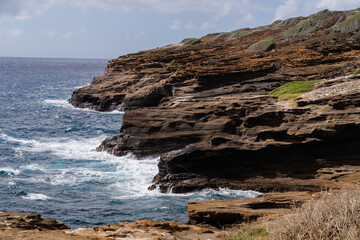 waves crash into rocks and cliffs along oahu, hawaii shoreline.