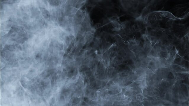 Smoke slowly floating through space against black background