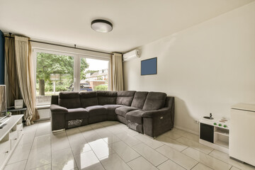 a living room with a couch, tv and large window looking out onto the street in front of the house