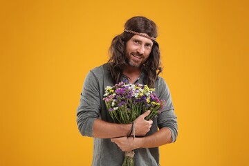 Hippie man with bouquet of colorful flowers orange background