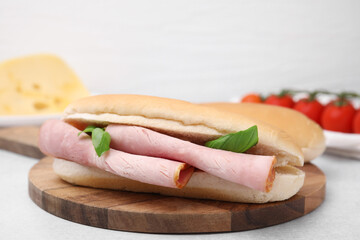 Delicious sandwich with ham and basil on white table, closeup
