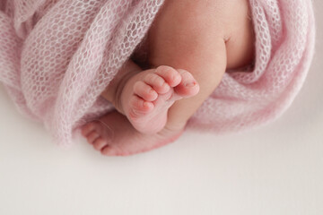 Close-up of tiny, cute, bare toes, heels and feet of a newborn girl, boy. Baby foot on pink soft coverlet, blanket. Detail of a newborn baby legs. Macro horizontal professional studio photo.  - obrazy, fototapety, plakaty
