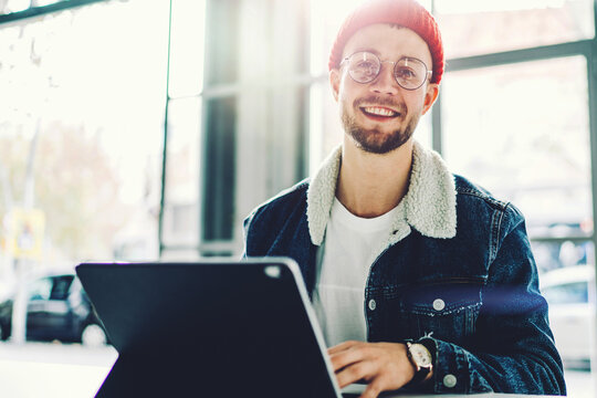 Cheerful hipster guy holding hands on modern tablet keyboard accessorise while posing for camera