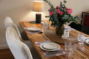 Beautiful table setting with bouquet and candles indoors. Roses and eucalyptus branches in vase