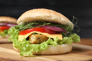 Delicious burger with tofu and fresh vegetables on wooden table, closeup