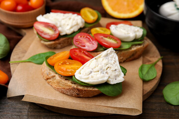 Delicious sandwiches with burrata cheese and tomatoes on wooden table, closeup
