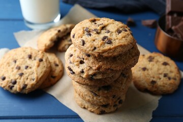 Tasty chocolate chip cookies and glass of milk on blue wooden table, closeup