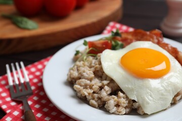 Tasty boiled oatmeal with fried egg served on table, closeup