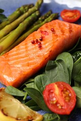 Tasty grilled salmon with tomatoes, asparagus, lemon and basil, closeup