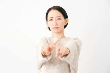 指でばつ印のジェスチャーをする中年女性　白背景