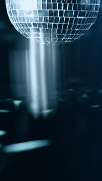 Mirror disco ball rotating, reflecting rays of light. 4k Dance Party Glitter Background. Vertical