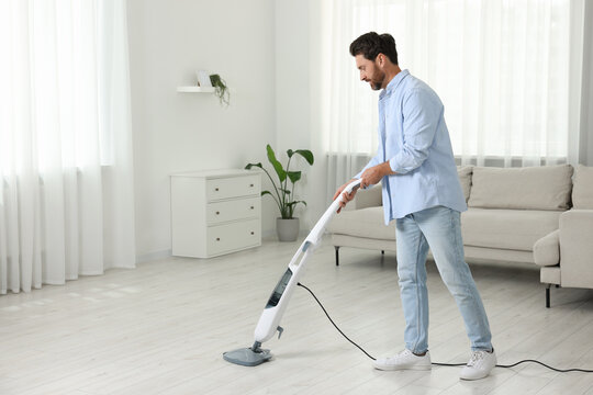 Man cleaning floor with steam mop at home. Space for text