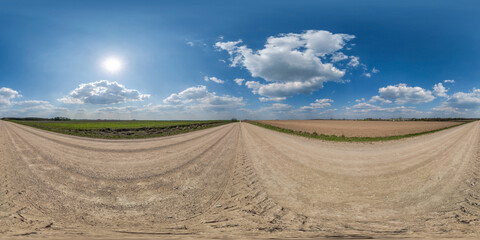 360 hdri panorama on gravel road with marks from car or tractor tires with clouds on blue sky in...