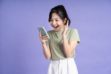 Portrait of beautiful asian woman using smartphone on purple background