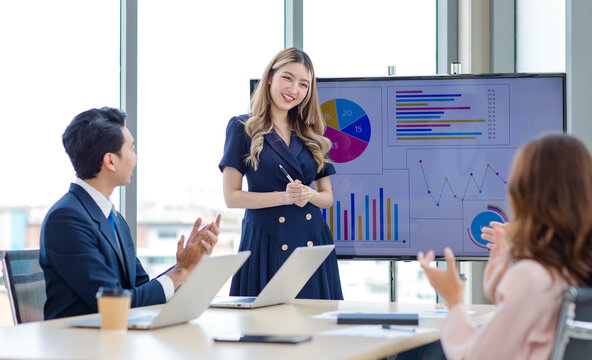 Asian Professional Successful Female Businesswoman Presenter Lecturer Speaker In Formal Business Outfit Stand Hold Pen Pointing Presenting Graph Chart Strategy Data On Computer Screen In Meeting Room