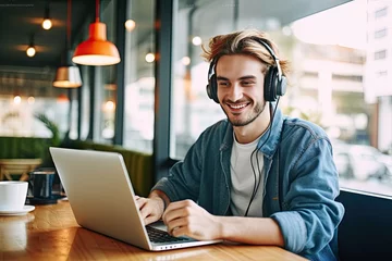 Foto op Plexiglas device laptop table sitting indoors rest headphones teenager male positive cafeteria learning playlist music favourite time enjoying guy hipster smiling happy portrait one person © sandra