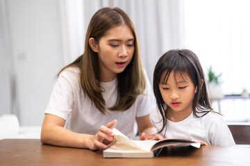 Portrait happy love asian family mother teach little daughter asian girl learn and study on table.Mom and asian young girl read book making lessons in homeschool at home.Education