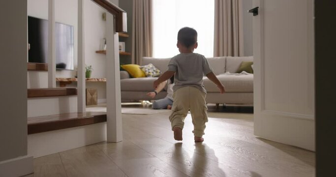 Mother and son, first steps. Cinematic Chinese, Japanese, Korean, Asian. Baby takes first step on floor to mother with bare feet. Compassion and emotional attachment between mother and son, parenthood