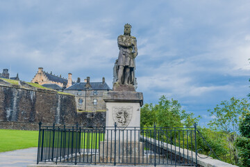 Statue of Robert the Bruce on concrete plinth under cloudy sky.