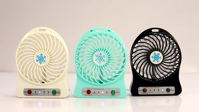 Rechargeable white, blue and black small fan on white background