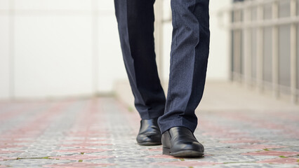 Legs of corporate executive impeccably dressed confidently walking outdoors. Man displays...