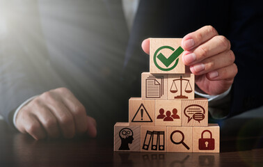 Regulatory compliance and business management. Businessman stacking wooden blocks. Check mark icon and lens flare light.