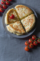 Homemade cheese filled savoury pies khachapury on grey plate served with tomatoes. Selective focus