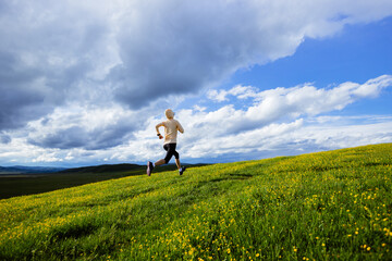 Woman trail runner cross country running at high altitude flowering mountain