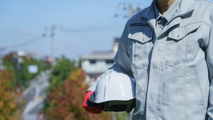 ヘルメットを持つ作業服の男性｜建設業・製造業などのイメージ