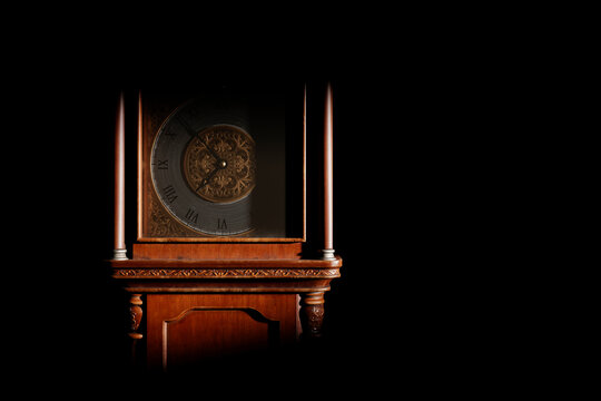 Close-up of the dial of an antique grandfather clock in a dark room, illuminated by light from the window.