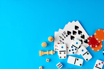 Items for playing chess, poker and domino on blue background studio shot