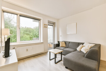 a living room with wood flooring and large windows looking out onto the trees outside in the photo is taken from inside