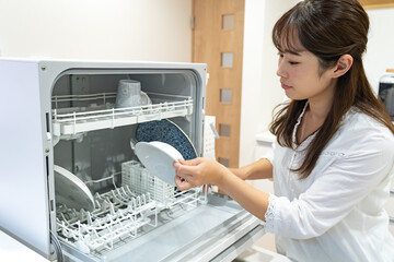 食洗機に皿を入れる女性