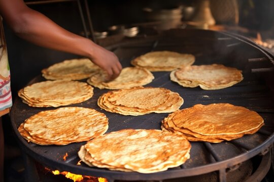 chapatis getting roasted on a griddle by hand