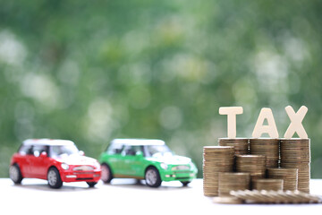Car tax concept, Stack of coins money with tax wooden text and miniature car model on natural green background, Saving money for car, Finance and car loan